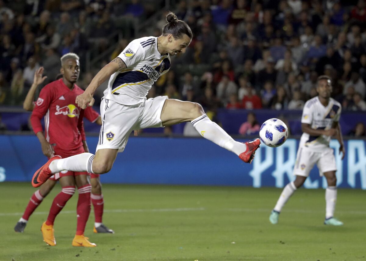 LA Galaxy forward Zlatan Ibrahimovic kicks the ball into the goal during the second half of an MLS soccer match against the New York Red Bulls, in Carson, Calif. The goal was later disallowed. Zlatan Ibrahimovic is returning to the Los Angeles Galaxy. A person with knowledge of the deal confirms the 37-year-old striker will play next season for the Galaxy. The person spoke on the condition of anonymity because the team had not yet formally announced it.