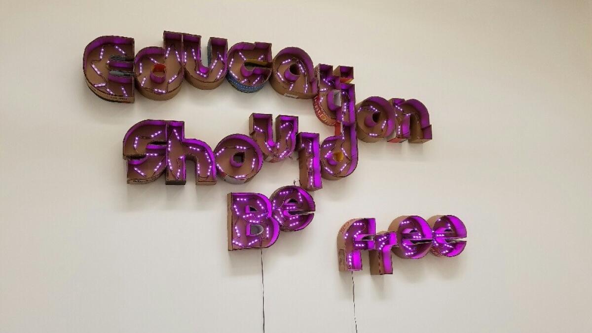 Andrea Bowers' sign, "Education Should Be Free," is made from electric lights in cut-up cardboard shipping boxes.