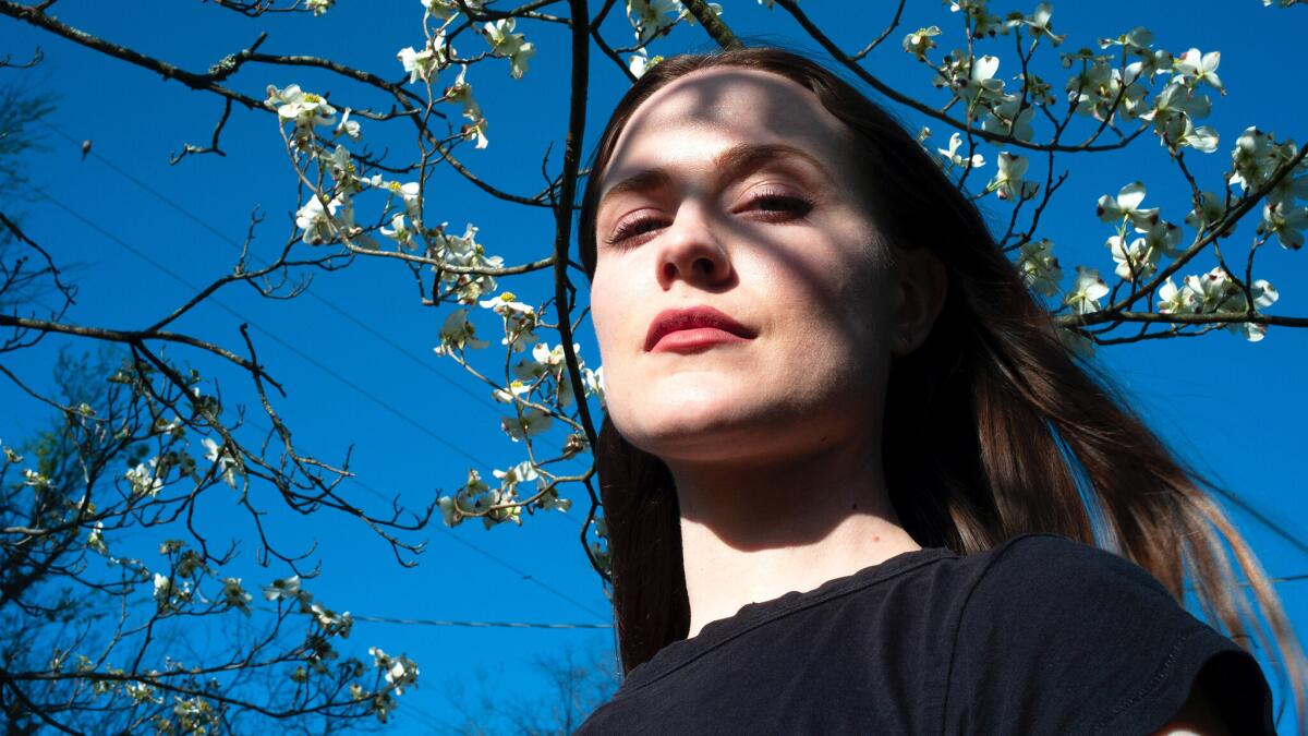 A woman's hair blows in the wind under a blooming tree