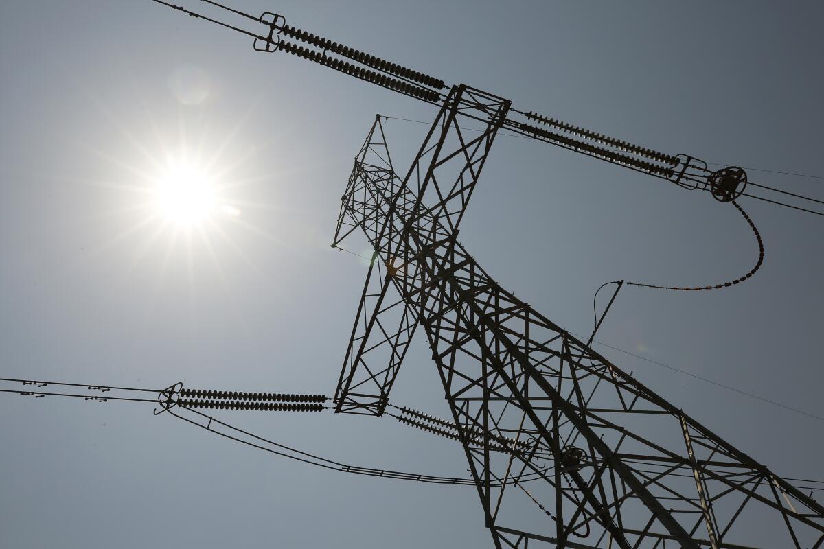 An electrical tower stretches up under a sunny sky.