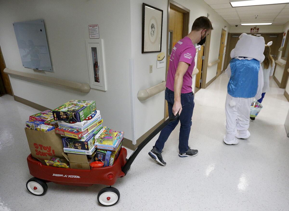Randall Auna-Villa from Starlight Children's Foundation pulls a wagon of toys at Fountain Valley Regional's pediatric unit.