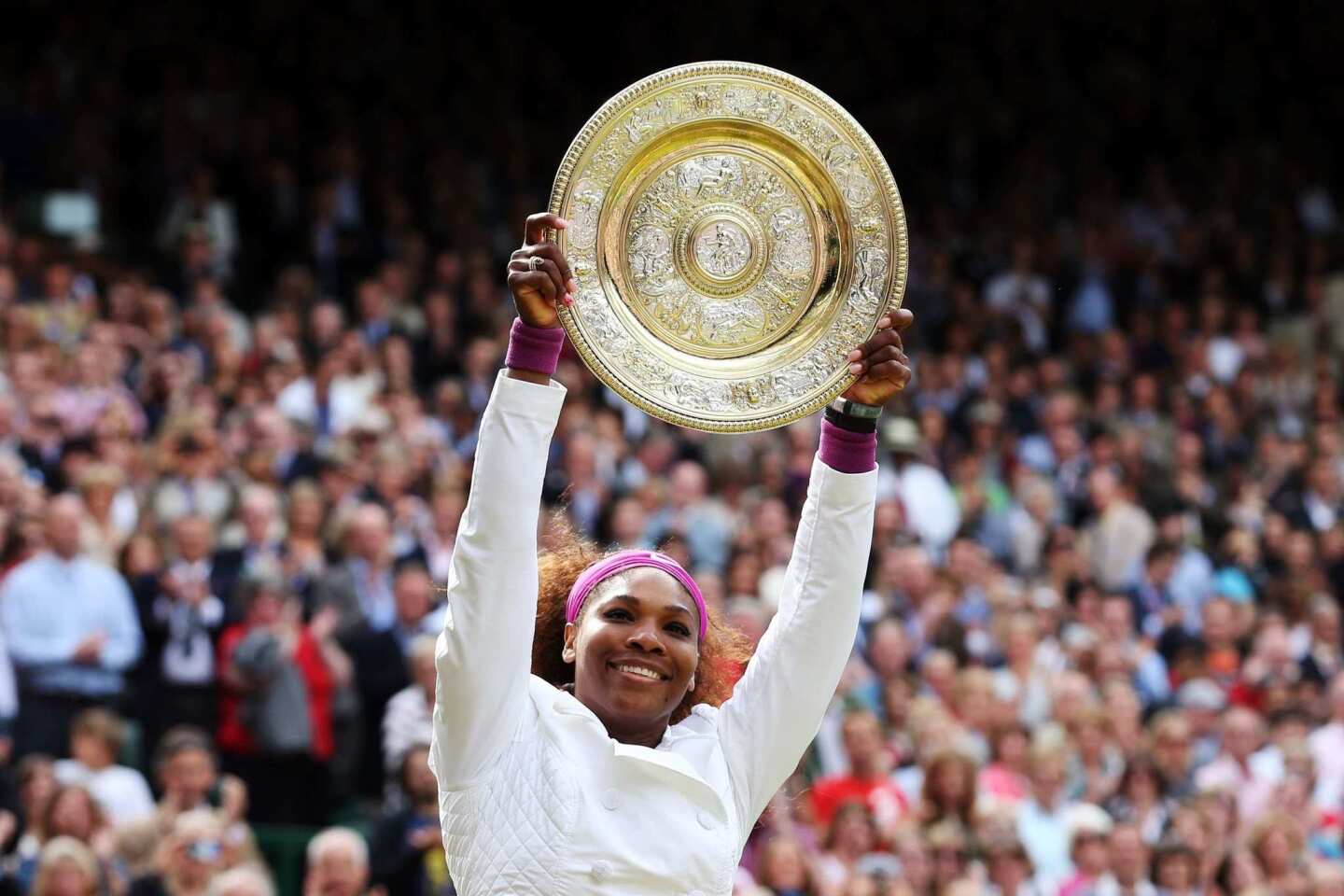 Serena Williams holds the winner's trophy aloft during the awards presentation after her three-set victory over Agnieszka Radwanska in the women's championship match at Wimbledon on Saturday.