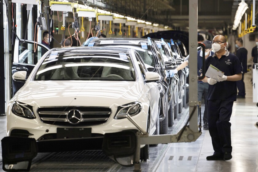 FILE - Workers inspect newly assembled cars at a Beijing Benz Automotive Co. Ltd factory, a German joint venture company for Mercedes-Benz, in Beijing on Wednesday, May 13, 2020. China's manufacturing activity improved in June after anti-virus controls that shut down Shanghai and other industrial centers were eased, a survey showed Thursday, June 30, 2022. (AP Photo/Ng Han Guan, File)