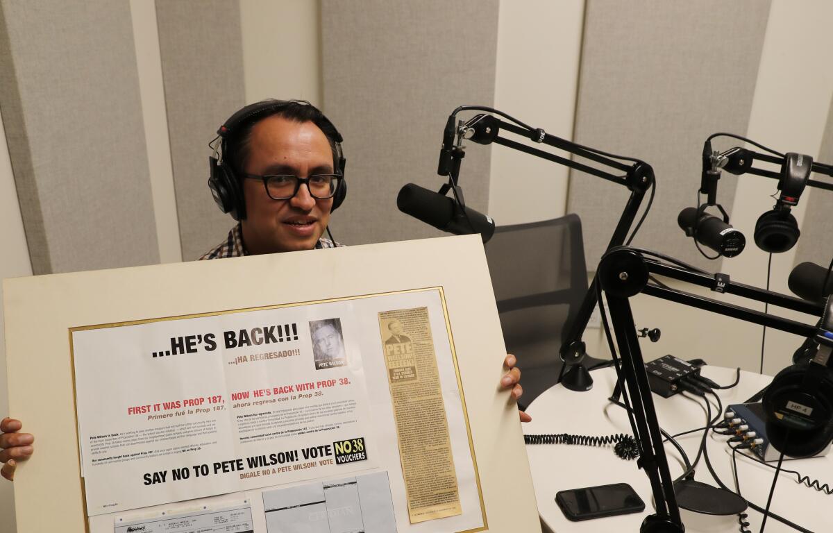 Gustavo Arellano holds a poster board with a campaign flier mounted next to a newspaper clipping.