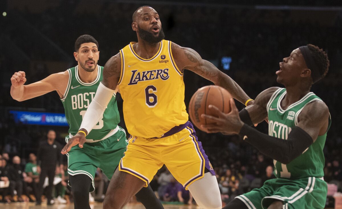 LeBron James slips Boston Celtics center Enes Freedom (13) and guard Dennis Schroder in the first half.