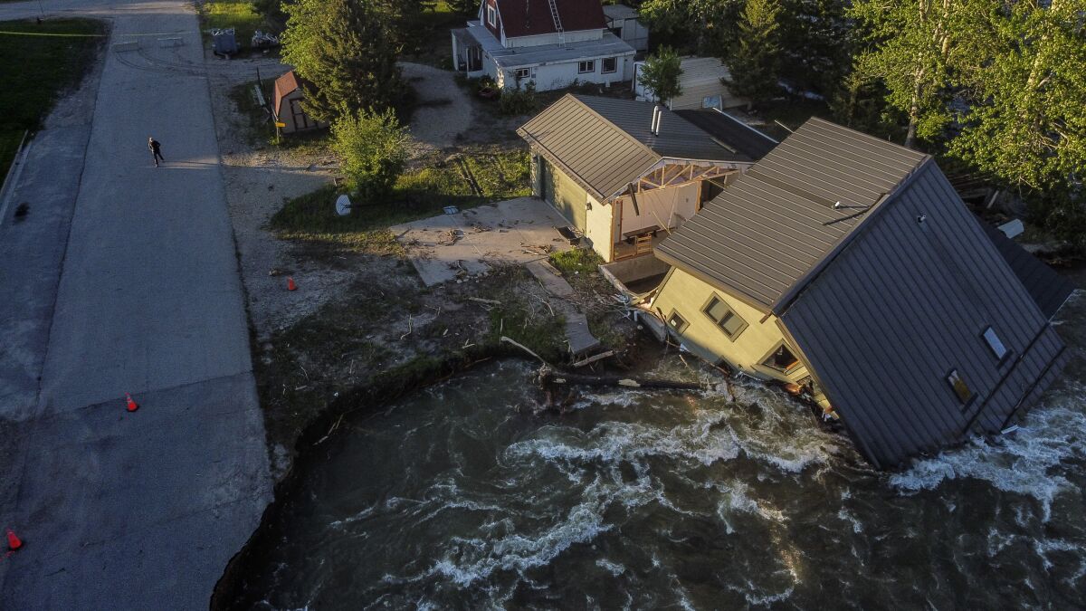 A house sits in Rock Creek after floodwaters washed away a road and a bridge in Red Lodge, Mont.