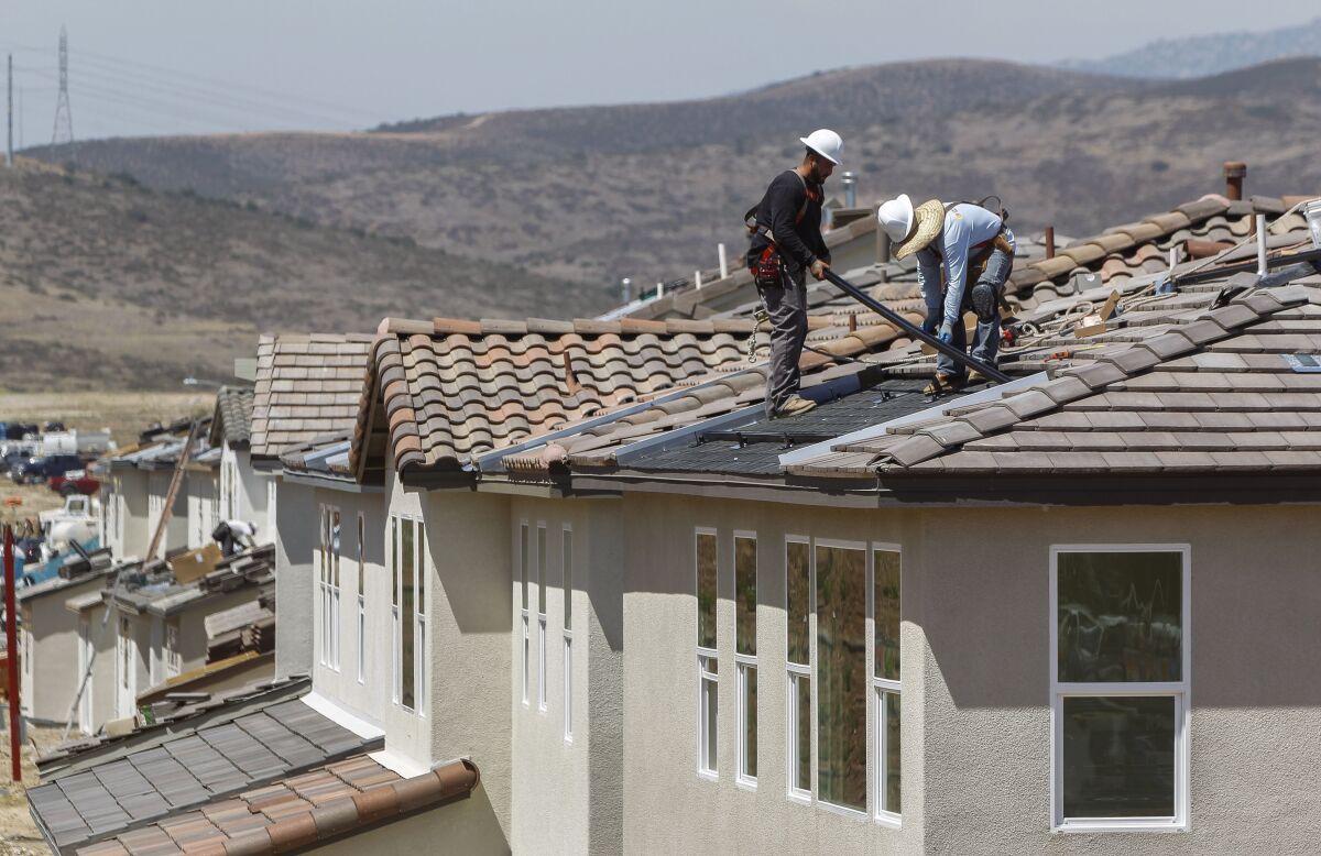 Workers install solar panels on a house