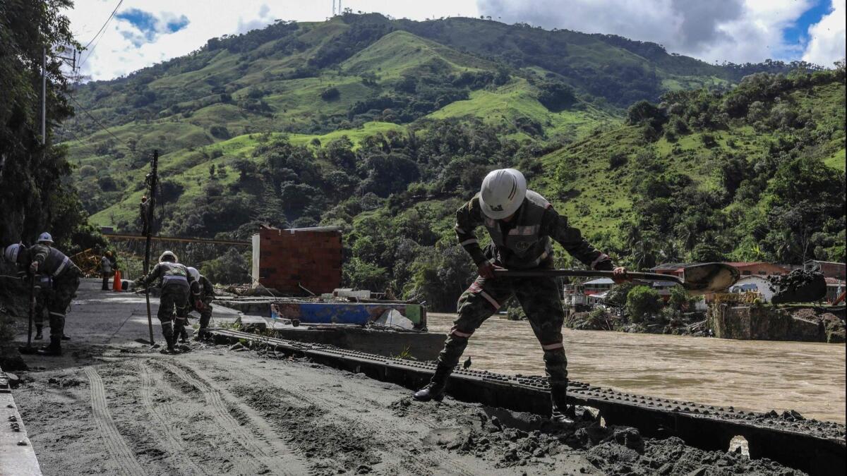 Soldiers clear mud from the streets of Puerto Valdivia, Colombia, after a landslide that blocked a diversion tunnel at a dam construction site, causing the Cauca River to overflow.