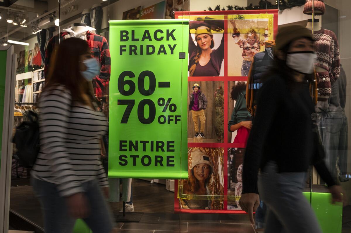 Customers walk past a Black Friday sale sign.