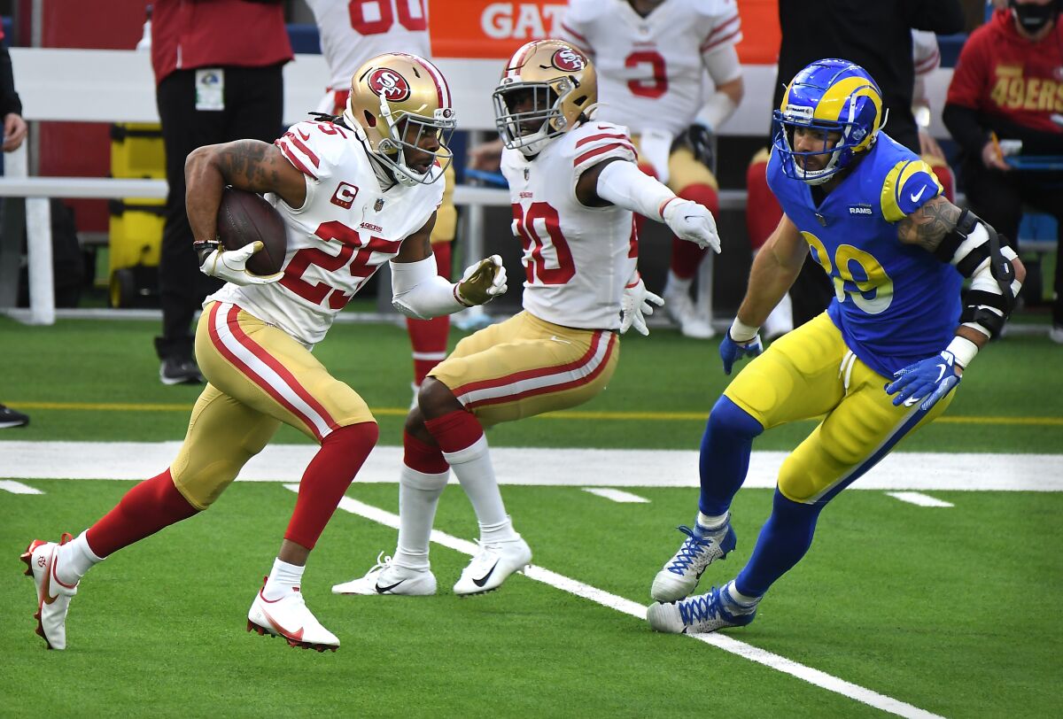 San Francisco 49ers cornerback Ricard Sherman runs back an interception in front of Rams tight end Tyler Higbee.
