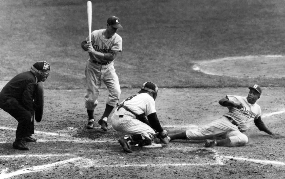 In this Sept. 28, 1955, photo, the Brooklyn Dodgers' Jackie Robinson safely steals home plate under the tag of New York Yankees catcher Yogi Berra in the eighth inning of the World Series opener at New York's Yankee Stadium. Berra, who played in more World Series games than any other major leaguer and was a three-time American League Most Valuable Player, died Tuesday at the age of 90.