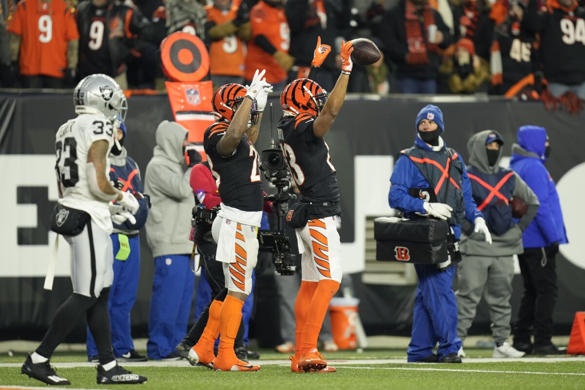Cincinnati Bengals' Tyler Boyd (83) and Joe Mixon (28) signal a touchdown in front of Las Vegas Raiders' Roderic Teamer (33) during the first half of an NFL wild-card playoff football game, Saturday, Jan. 15, 2022, in Cincinnati. Boyd made the touchdown reception. (AP Photo/AJ Mast)