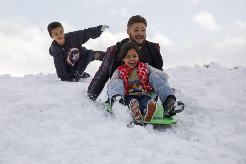 Derek Graham rides a sled with Paige, 6, (in red) and Henry, 7, rear, of Bakersfield as they play in the snow after a winter storm on Friday, November 29, 2019 in Lebec, Calif. The family had planned to go to Mexico but the snow and road closures changed their plans. (Patrick T. Fallon/ For The Los Angeles Times)