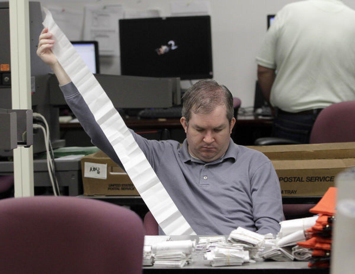 A Miami-Dade Elections Department employee tallies absentee ballot reports in Doral, Fla.