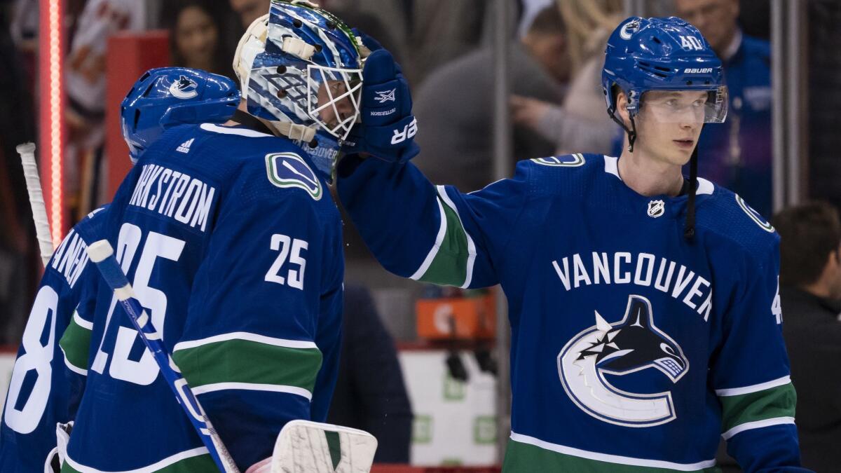 Vancouver Canucks goalie Jacob Markstrom, left, is congratulated by teammate Elias Pettersson after defeating the Calgary Flames 4-3 on Saturday.
