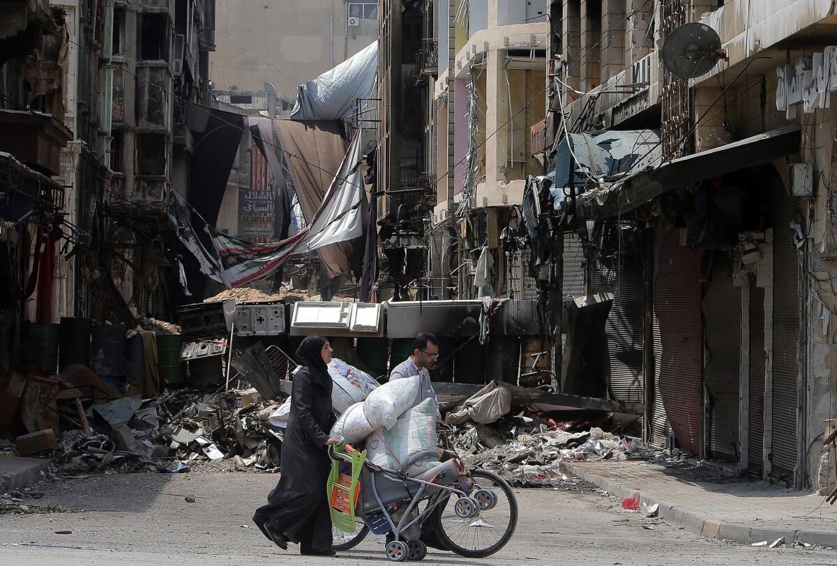 Syrians cart their belongings through the streets of a destroyed neighborhood of the Old City of Homs on May 12.