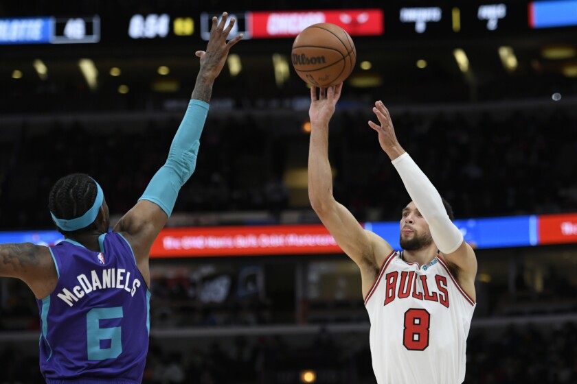 El base de los Bulls de Chicago Zach LaVine lanza ante el alero de los Hornets de Charlotte Jalen McDaniels durante la primera mitad del partido de la NBA, el lunes 29 de noviembre de 2021, en Chicago. (AP Foto/Paul Beaty)