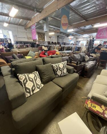 An olive green sofa with throw pillows among the wares at Out of the Closet Super Store 