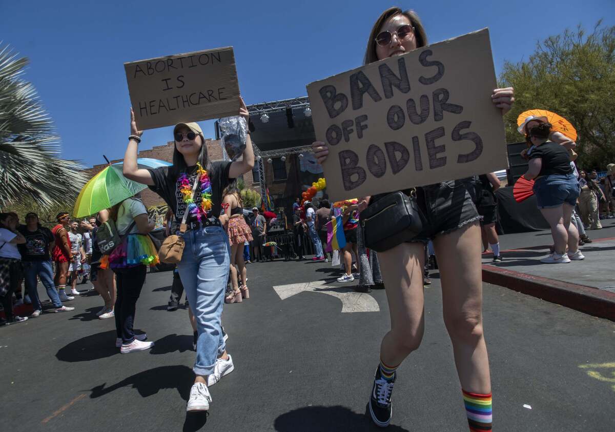 Women march with signs reading "Abortion is Healthcare" and "Bans Off Our Bodies"