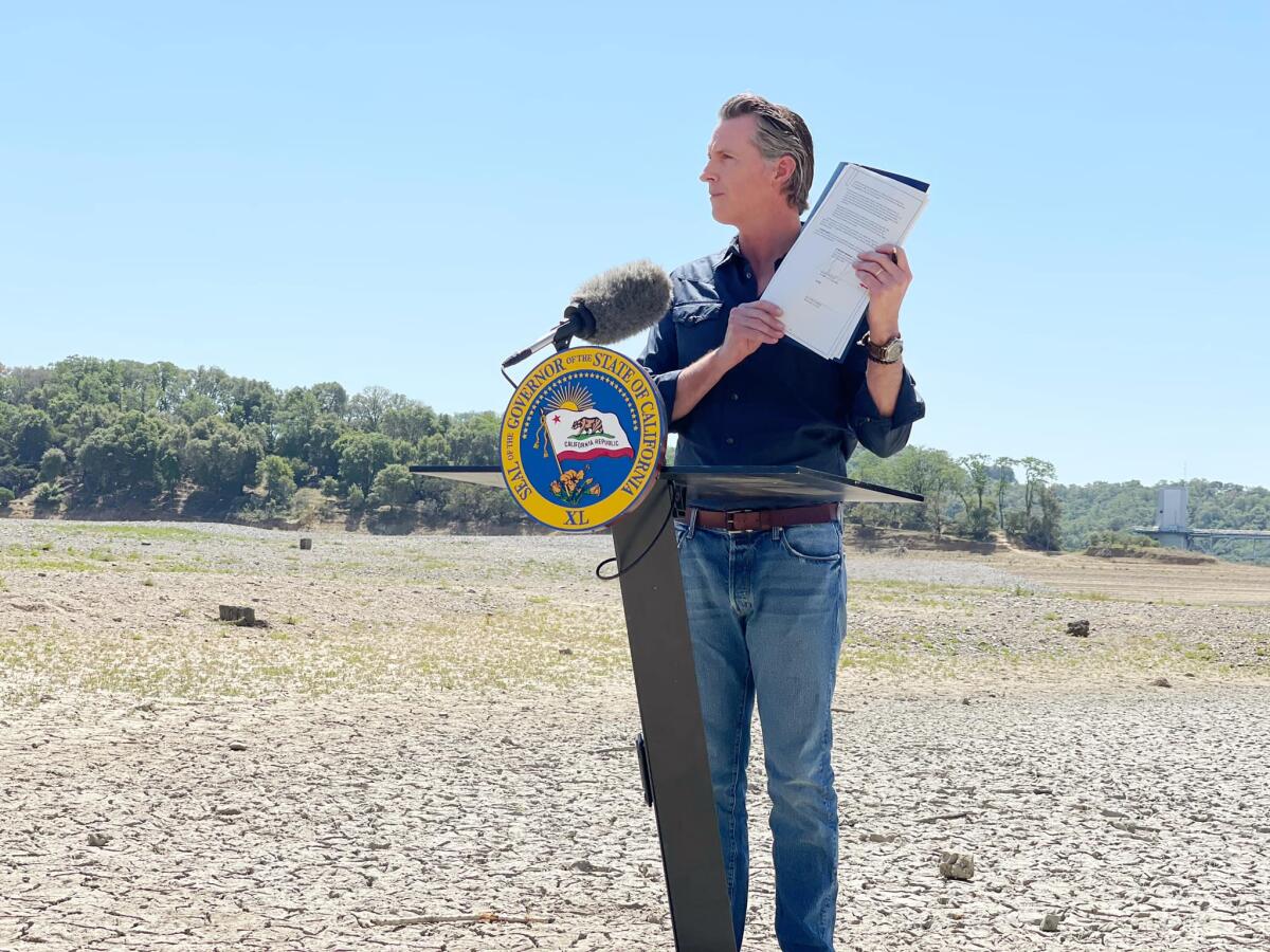 Gov. Gavin Newsom stand in a dry lake bed.