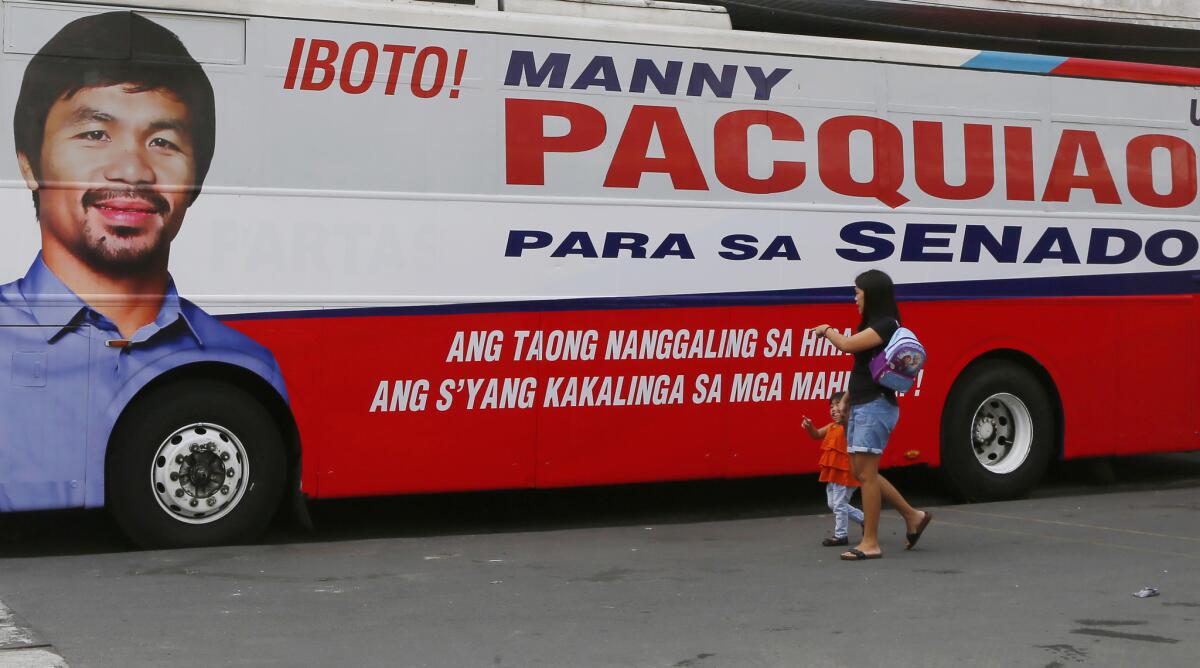 A woman and child walk past a bus with an image of senatorial candidate and boxer Manny Pacquiao on Feb. 17.