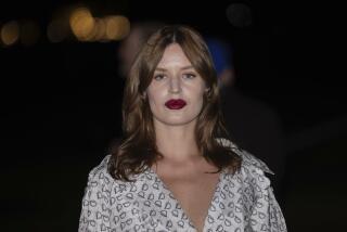 Georgia May Jagger poses in a white printed dress and dark red lipstick at the Burberry Winter 2024 fashion show in London