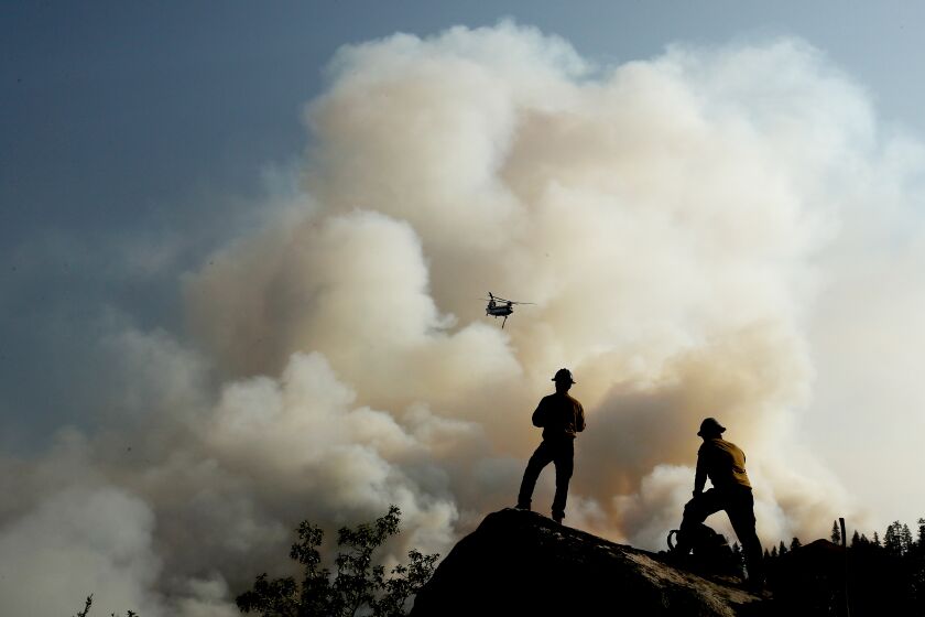 JANESVILLE, CALIF. - AUG. 189 2021. Firefighters watch a helicopter battle the Dixie Fire as it burns through mountainous and forested terrain near Janesville on Thursday, Aug. 19, 2021. (Luis Sinco / Los Angeles Times)