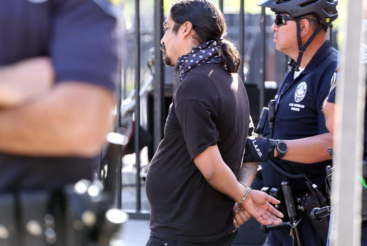 A protester is held by police after a fight broke out at the Los Angeles Times en Espanol stage 