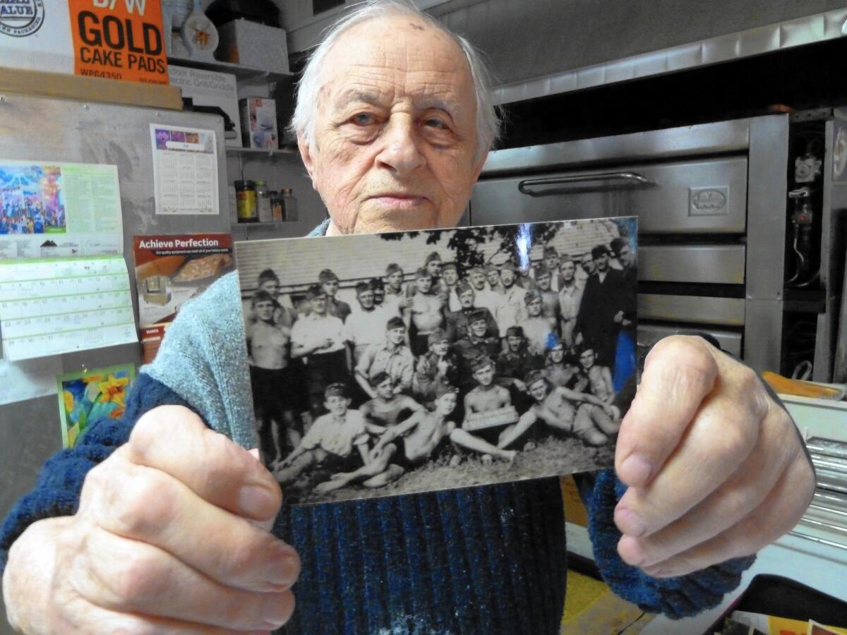 Ernie Feld, who survived World War II by baking for Nazi SS officers, shows a wartime photo of himself and other prisoners. Now 90, he runs a bakery near Lake Tahoe.