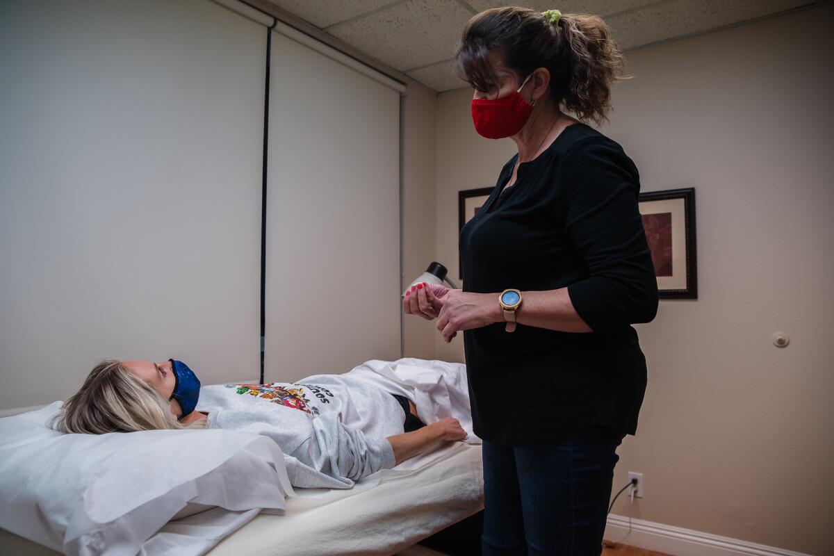 Rachael Lackner, a long COVID-19 patient in San Diego, speaks to Tracey Whitney before getting acupuncture.