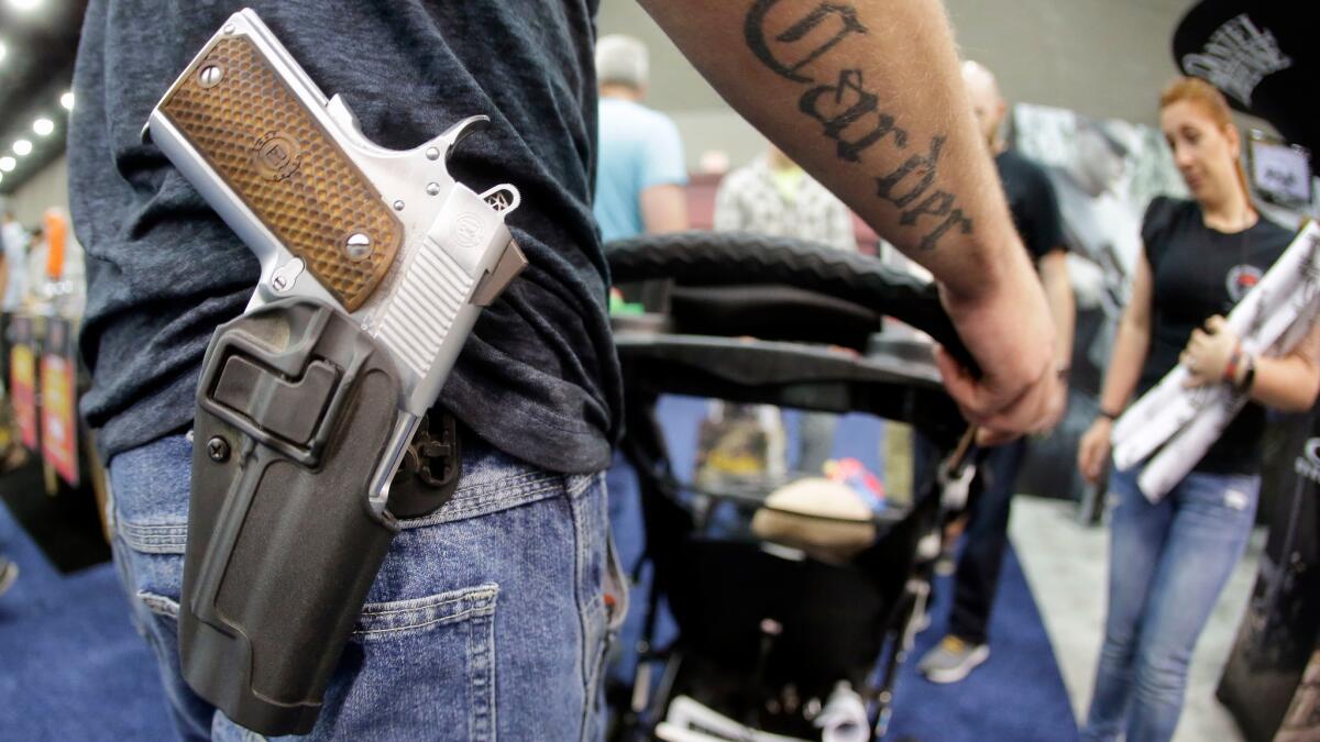 A man wears his handgun in a holster as he pushes his son in a stroller at the National Rifle Association convention in Louisville, Ky. May 21. Attendees at the convention are permitted to carry firearms under Kentucky's open carry law.