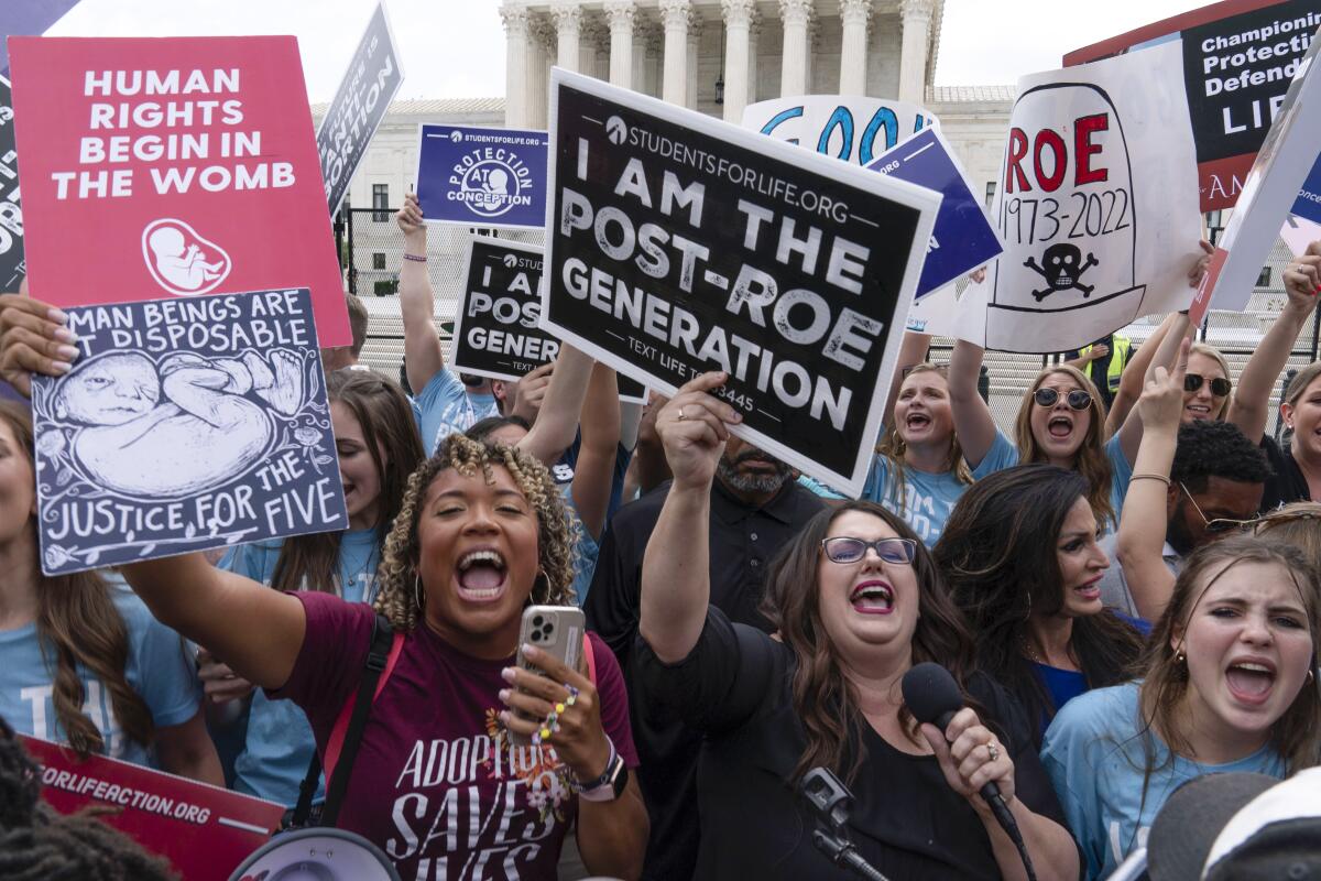 Antiabortion demonstrators hold signs reading "I am the post-Roe generation" and "Human rights begin in the womb."