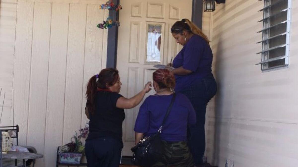 From left, janitors Leticia Soto and Dora Diaz look on as Jasmin Castillo knocks on the door of a mobile home in Las Vegas.
