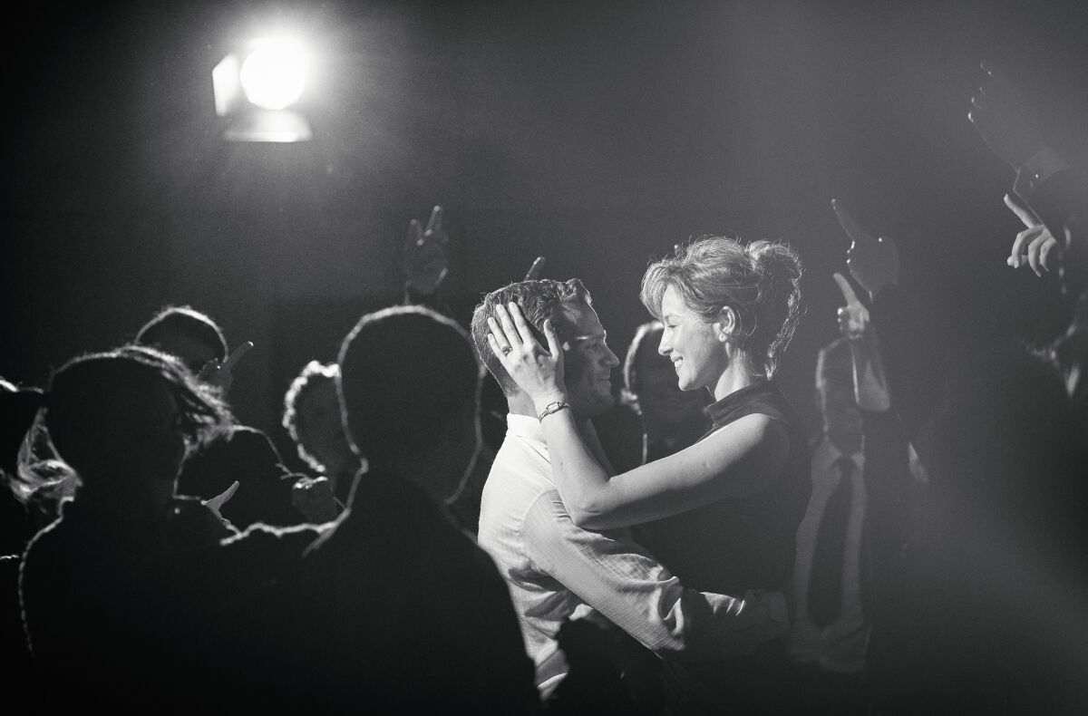 A black-and-white image of Jamie Dornan dancing in a crowd with Caitríona Balfe
