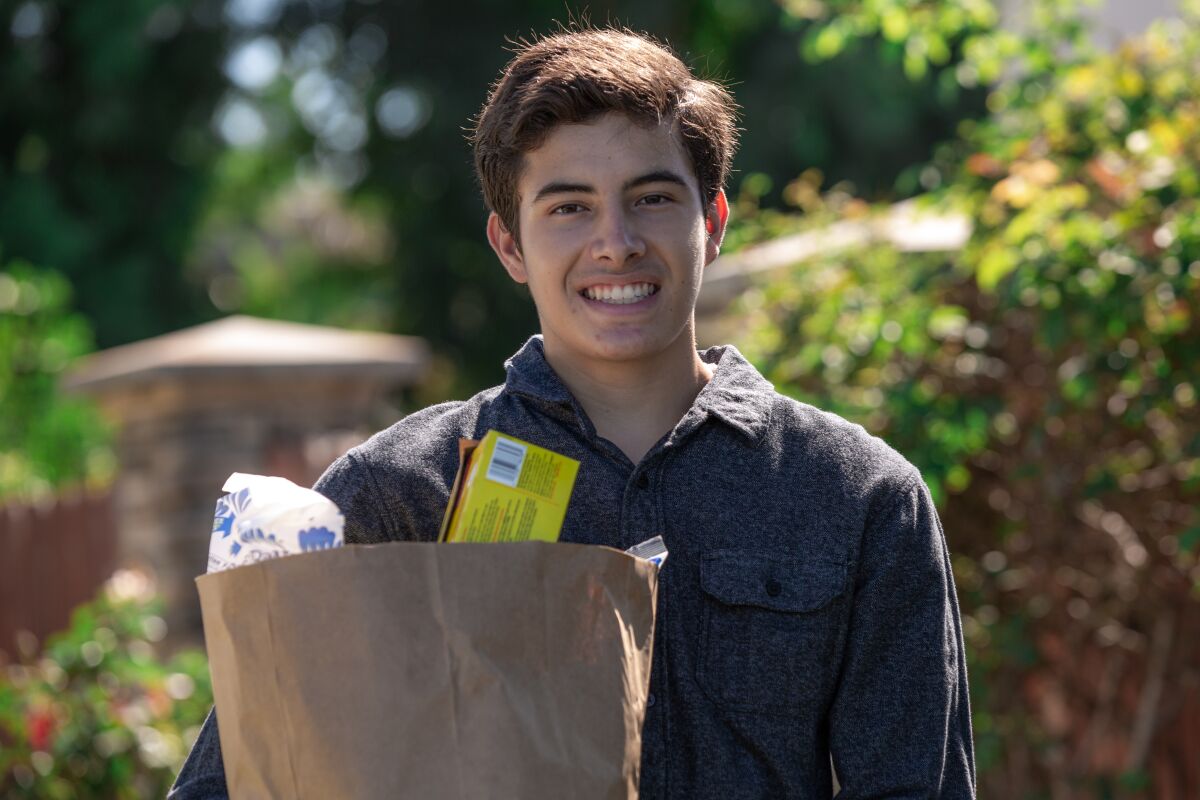 Nolan Mejia, standing outdoors and holding a bag of groceries