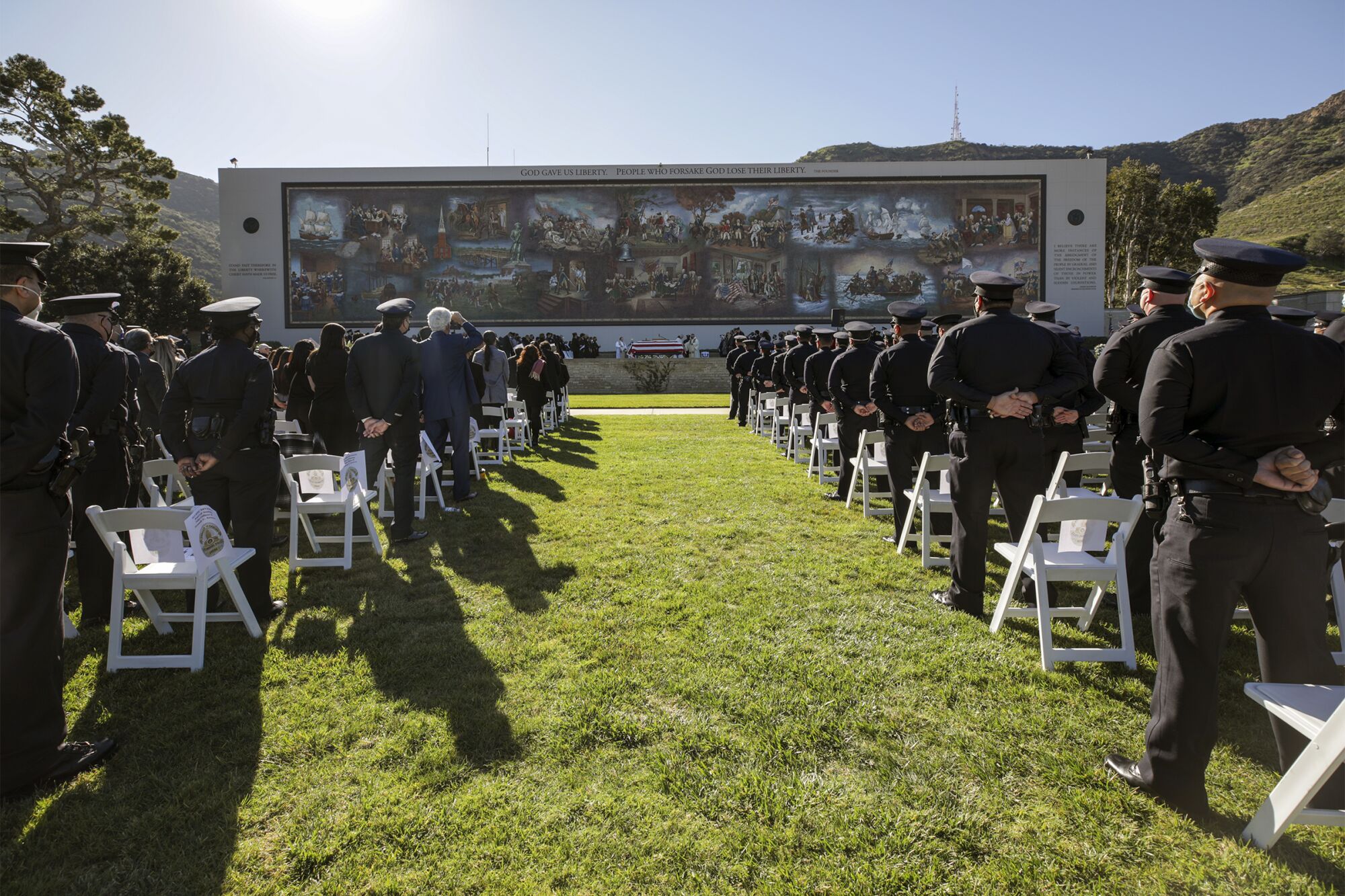 People attend a funeral at Forest Lawn-Hollywood Hills in front of the 'Birth of Liberty' mosaic.