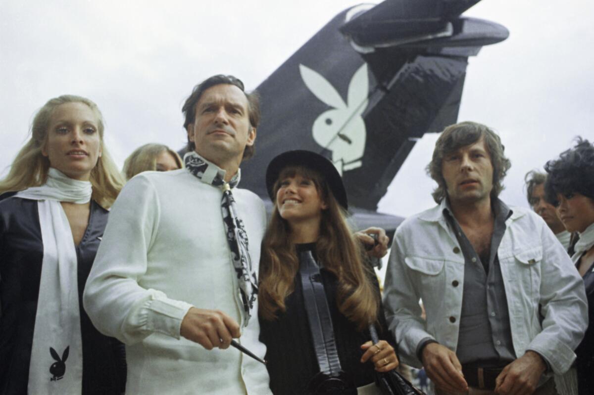 Playboy publisher Hugh Hefner, second from left, arrives in Paris in 1970 with his girlfriend Barbi Benton, center, and film director Roman Polanski.