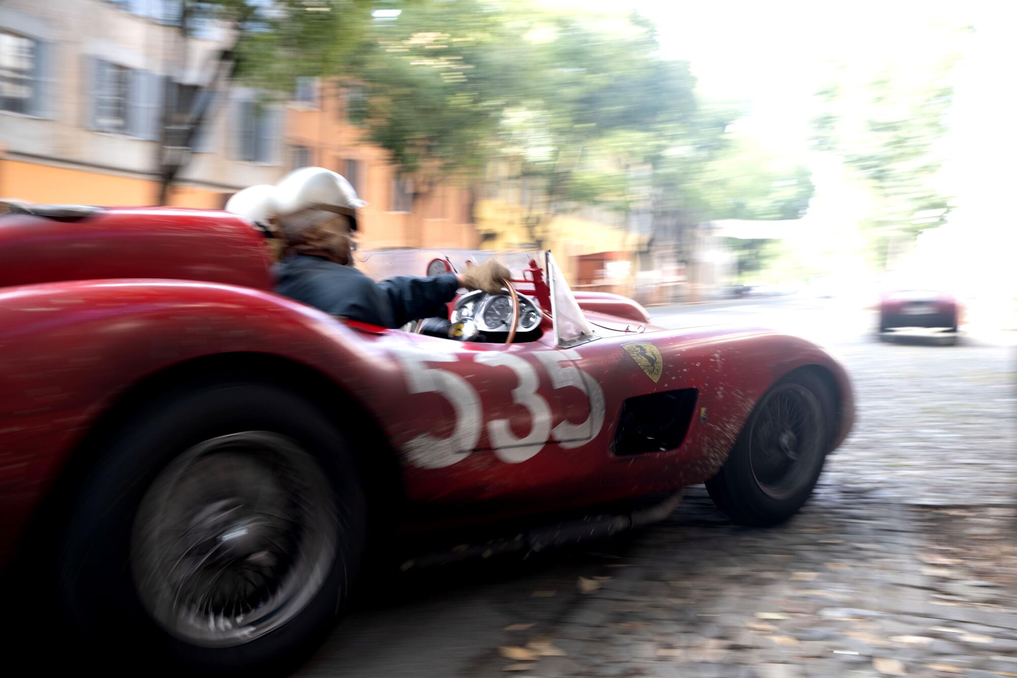 A red race car speeds down an Italian road.