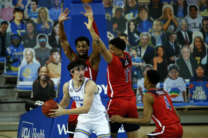 UCLA guard Jaime Jaquez Jr. (4) looks to pass the ball while defended by Arizona during the first half of an NCAA college basketball game Thursday, Feb. 18, 2021, in Los Angeles. (AP Photo/Ringo H.W. Chiu)