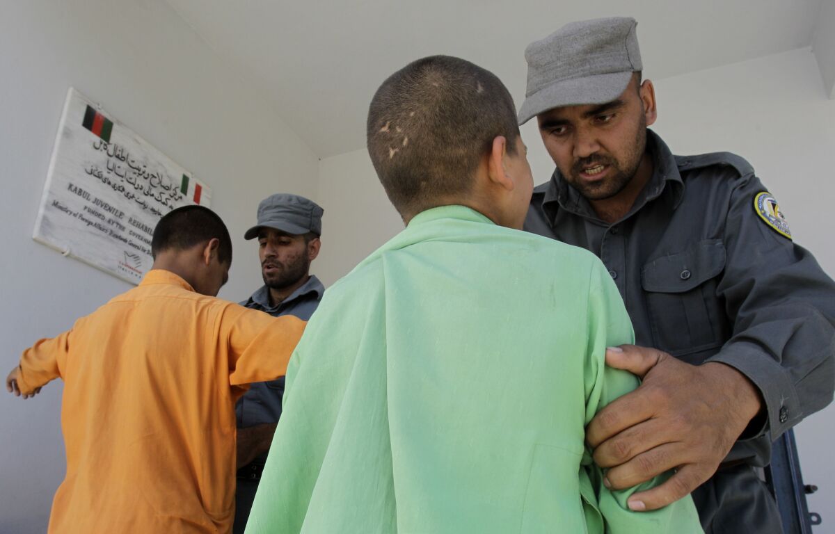Guards search two boys before they return to their cells.