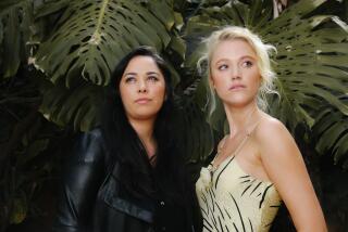 Los Angeles, CA - May 27: Director Chloe Okuna, left, stands with lead actor Maika Monroe, right, for the horror-thriller "Watcher" for a portrait at at her home on Friday, May 27, 2022 in Los Angeles, CA. (Dania Maxwell / Los Angeles Times)