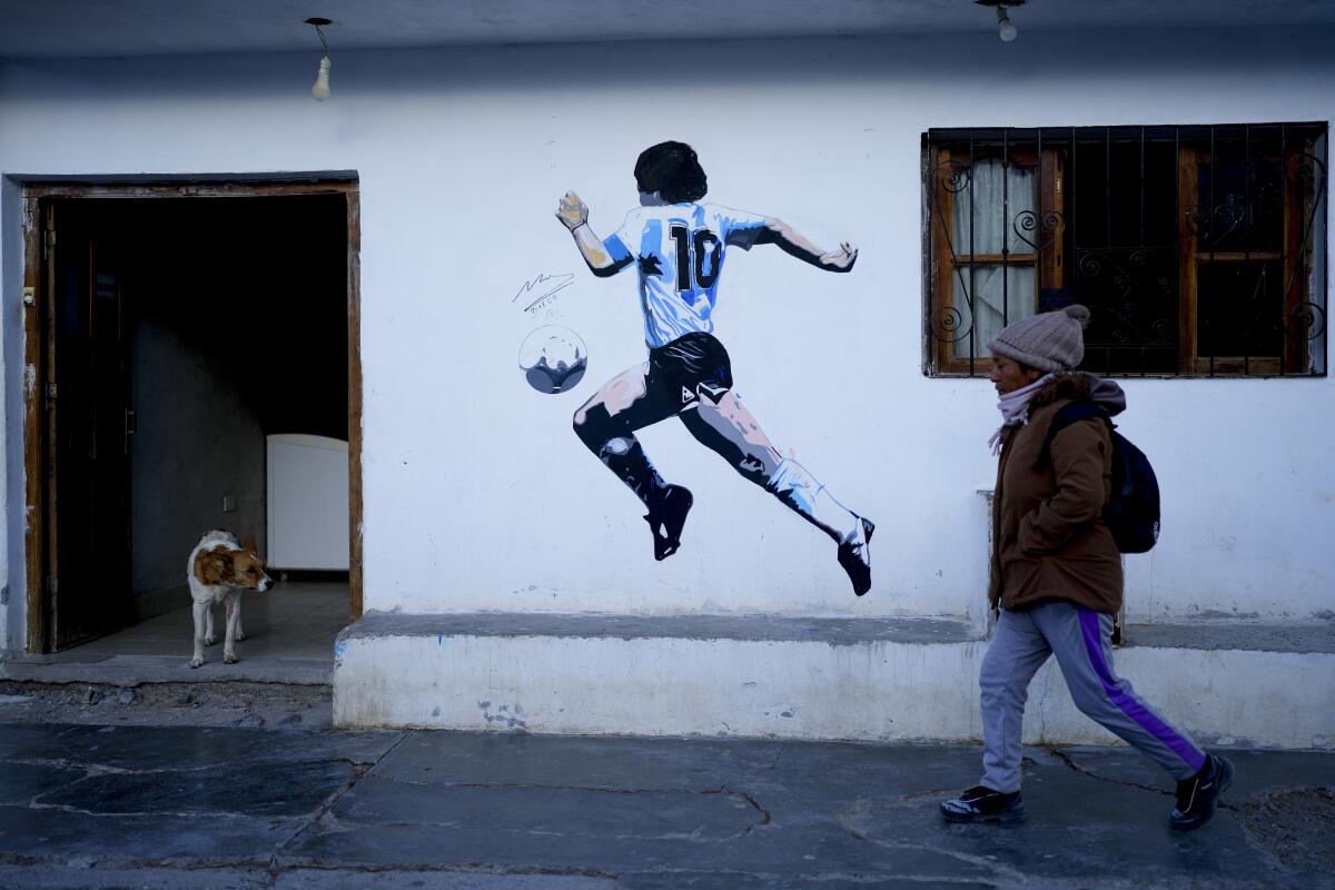 Una mujer camina por delante de un mural de la leyenda del fútbol argentino Diego Maradona, 
