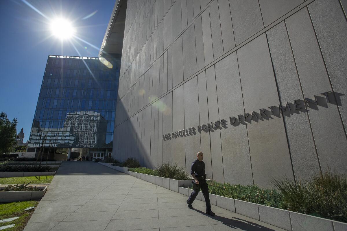 The multi-story concrete L.A. police headquarters facade, with blue sky and sunshine in the background.