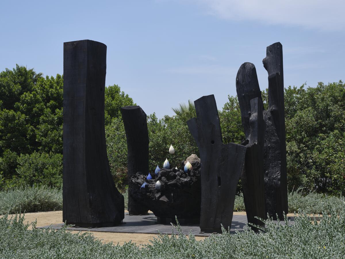 Tall black pillars in a circle in an outdoor sculpture installation