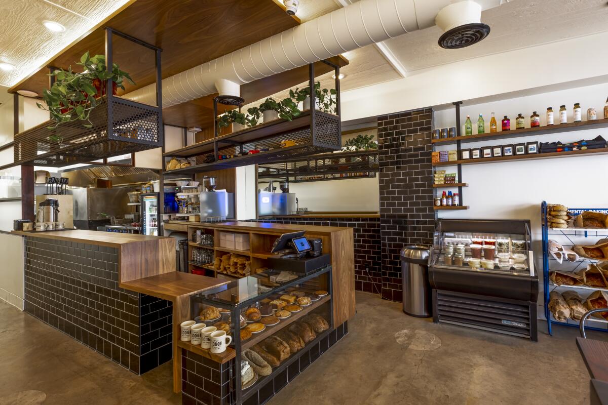 An interior photo of the register at the new Lodge Bread Co., featuring wood, black tile and plants.