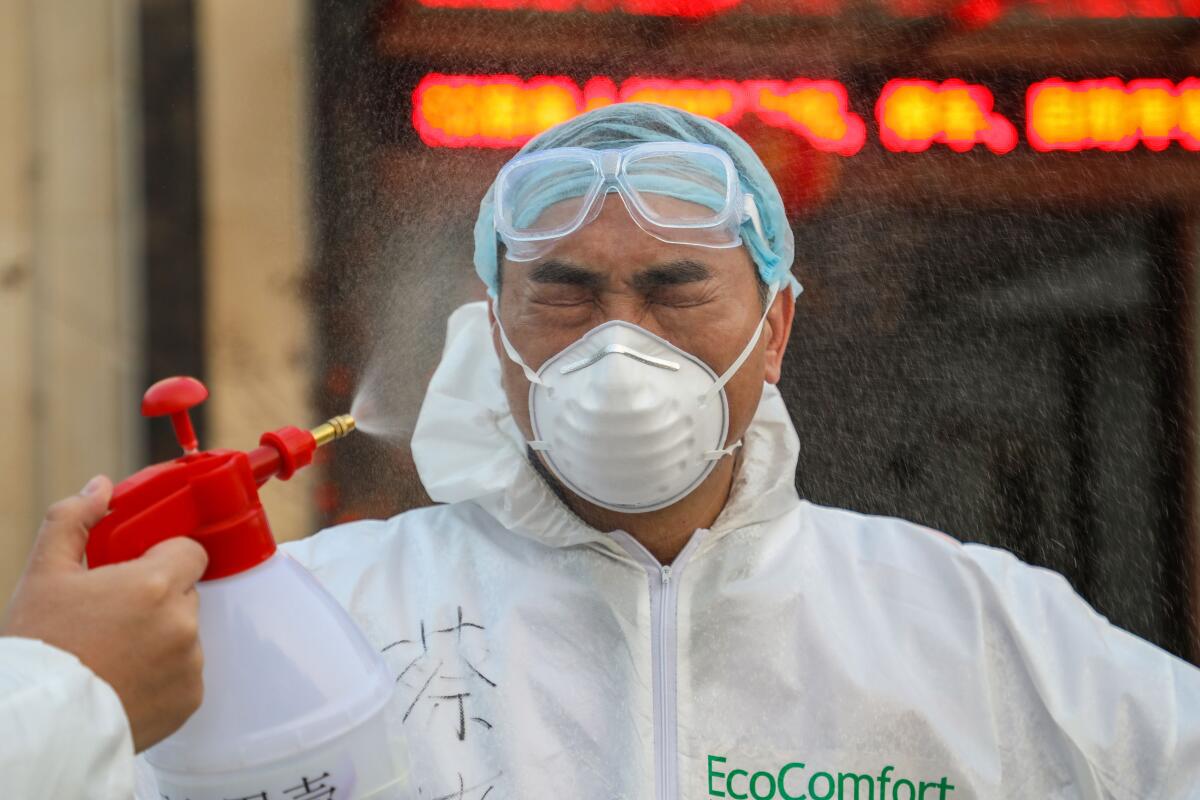 Un colega desinfecta a un médico en una zona de cuarentena en Wuhan, el epicentro del brote de coronavirus de China, en la provincia de Hubei.
