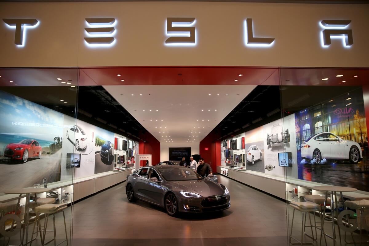 Shoppers look at a Tesla Motors vehicle on the showroom floor at the Dadeland Mall in Miami.