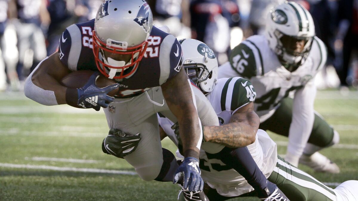 New England Patriots running back James White drags New York Jets defensive back Rontez Miles as he dives across the goal line for a touchdown during the first half on Dec. 30.