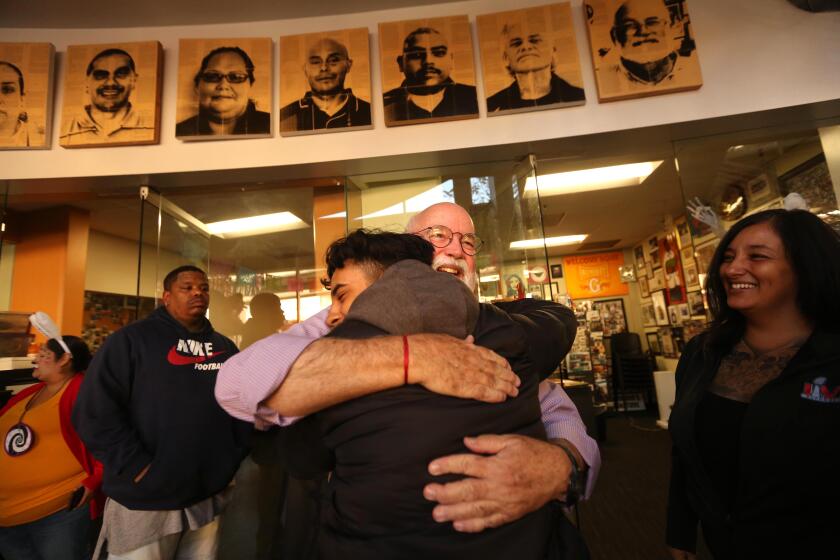 LOS ANGELES, CA - OCTOBER 28, 2022 - - Father Greg Boyle, founder and director of Homeboy Industries, hugs Oscar Carranza, 20, at the company's headquarters in downtown Los Angeles on October 28, 2022. Father Greg spends the mornings counseling constituents, offering direction and assistance to former gang members. For over 30 years Homeboy Industries has offered programs to assist high-risk youth, former gang members and the recently incarcerated with a variety of free programs, such as mental health counseling, legal services, tattoo removal, curriculum and education classes, work-readiness training, and employment services. (Genaro Molina / Los Angeles Times)