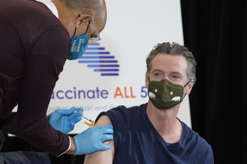 Dr. Mark Ghaly, Secretary, California Health and Human Services, left, inoculates California Gov. Gavin Newsom, right, at the Baldwin Hills Crenshaw Plaza in Los Angeles Thursday, April 1, 2021. Newsom was vaccinated with the new one-dose Janssen COVID-19 vaccine by Johnson & Johnson. (AP Photo/Damian Dovarganes)